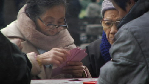 Lady playing cards in Shanghai, bundled up.
