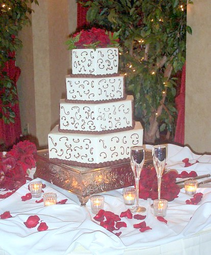 Four step wedding cake with the red flowers on the top.