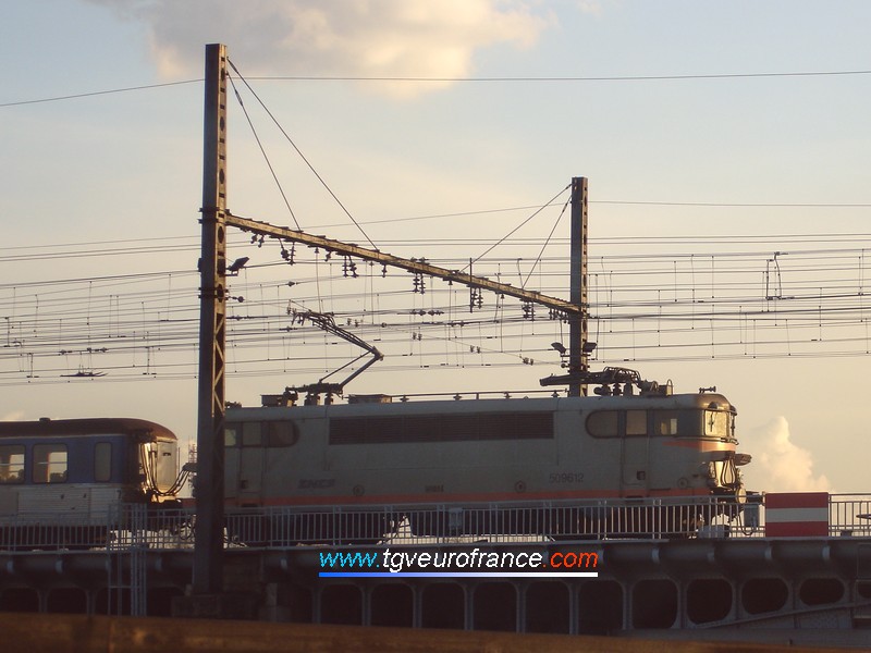 Coucher de soleil sur une locomotive électrique BB 9600 SNCF franchissant le Rhône en pousse d'une rame RIO assurant une liaison TER Mâcon - Lyon