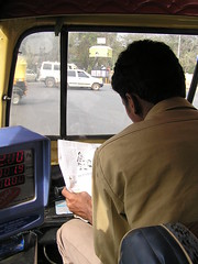 Conductor de rickshaw leyendo el periódico
