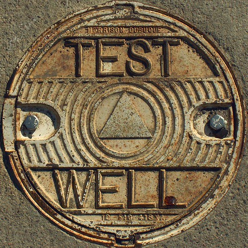 a picture of a manhole cover with the text at the top, a triangle in the center, and well at the bottom on it.