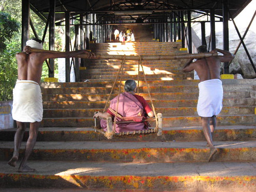 An old lady being carried up the stairs to the temple..