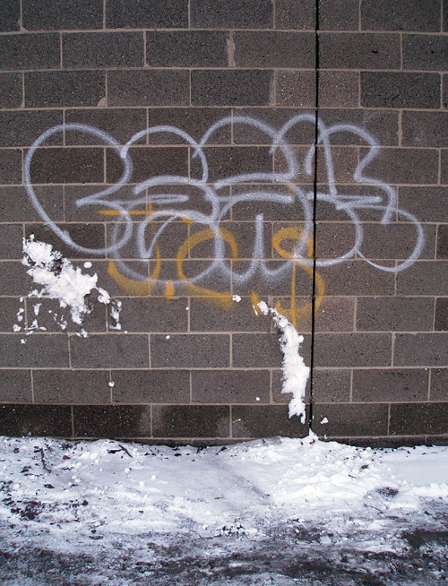 brick wall with graffiti and snow