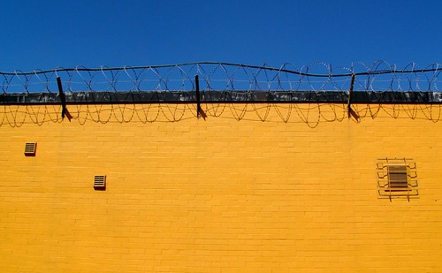 Muro amarillo con alambre de espino en la parte superior