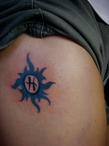 Symbol of pisces designs tattoo in the middle of blue sun
