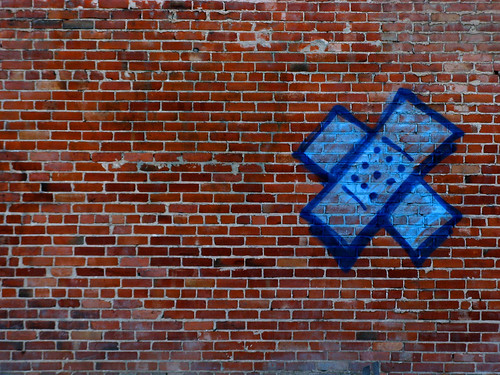 graffiti of blue bandaids, one crossed over the other to make an x, on a brick wall