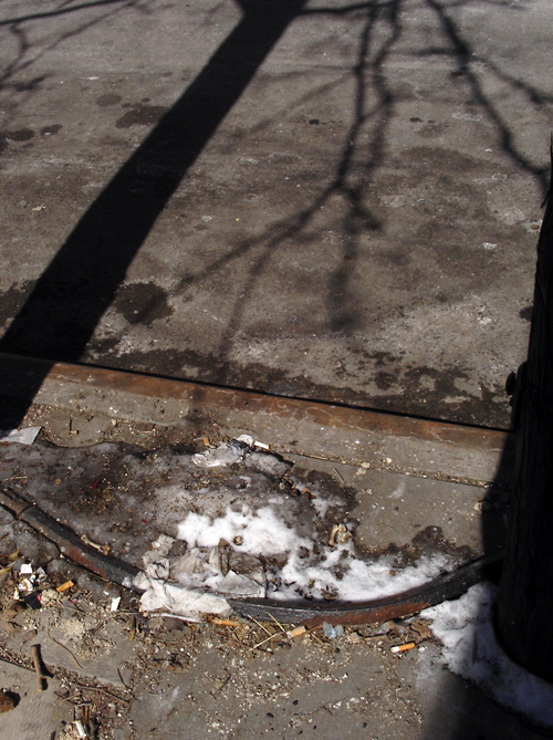 last remains of snow, with shadows and cigarette butts