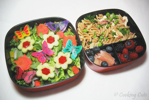 [left bento tier with decorated salad; right bento tier with pasta and fruit]
