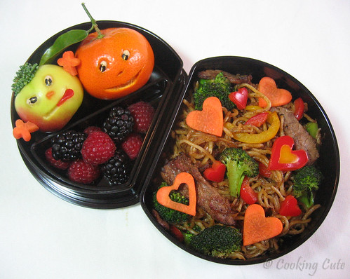 [half moon bento with carved fruit, berries, and yakisoba]
