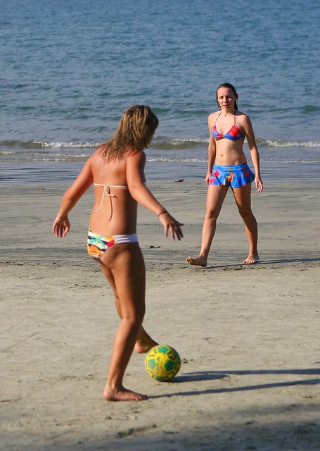 Two bikini girls playing beach football