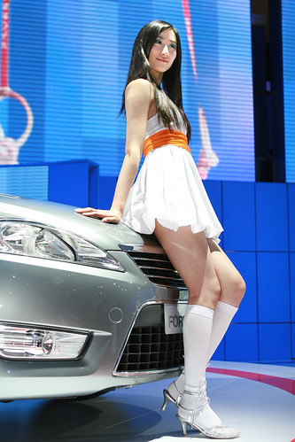 Asian model in white mini skirt near silver car