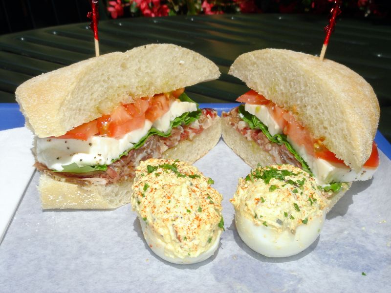 Prosciutto di parma sandwich with fresh mozzarella, fresh basil and fresh tomatoes and stuffed eggs