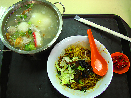 Mini Wok Noodle - piping hot soup with fish balls, slivers of meat, crab sticks and egg inside a metal wok with a burner underneath, paired with egg noodles with mushrooms and vegetables