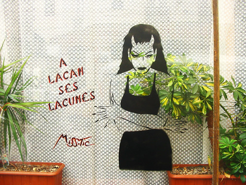 graffiti from miss tic: a woman with devil horns, hands crossed in front of her, next to the words "A Lacan Ses Lacunes"