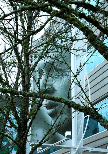 Bill Bowerman poster obscured by mossy trees outside Nike Corporate Headquarters, Beaverton, Oregon winter spring 2004-2005. Coach Bill Bowerman invented of waffle sole for running shoes and helped to spread the gospel of jogging by Wonderlane