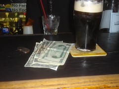 Glass of Guinness at a bar and cash