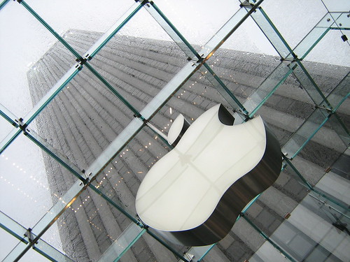 an apple logo in the foreground with a skyscraper rising behind it