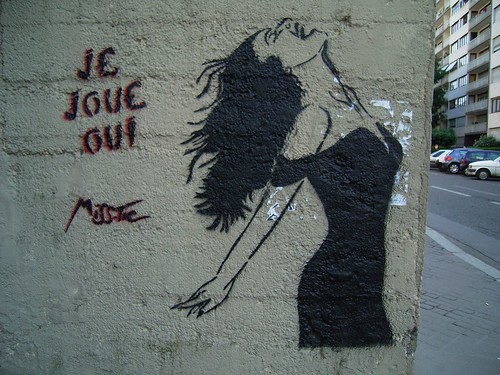stencil graffiti: a woman with her head thrown back, laughing or yelling with joy, and the words "je joue oui"