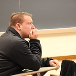 A student intently listening to a presentation given by one of his fellow classmates.