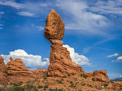 Two balanced rocks against puffy white clouds in Arches National Park