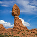 Two balanced rocks against puffy white clouds in Arches National Park