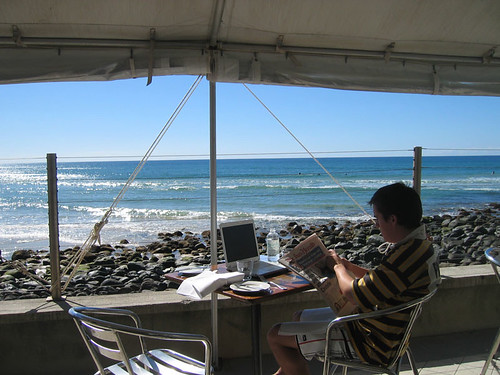 Man eating breakfast and surfing Internet at the beach.
