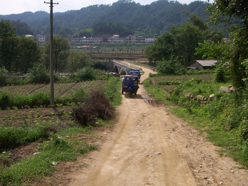 3-wheeled chinese tractor/trucks traveling up country dirt road