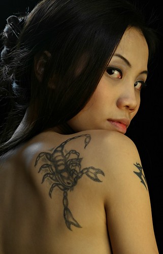 Eva, sexy Latina girl showing a scorpio tattoo on her shoulder