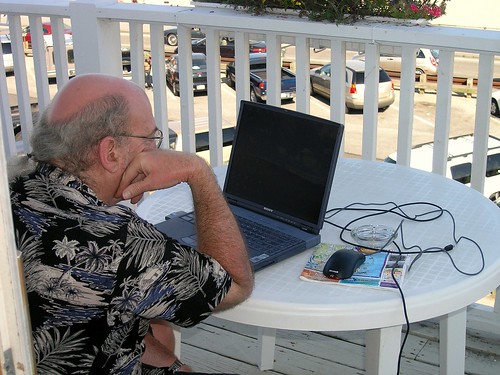 Man using laptop on a deck.
