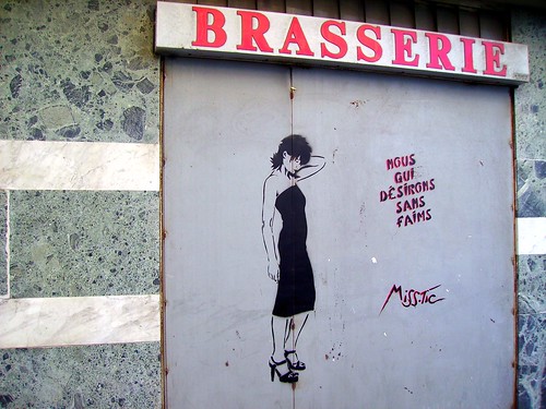 graffiti by miss tic: a slender woman standing, one hand behind head, head a bit bowed, next to the words: "Nous qui désirons sans faims"