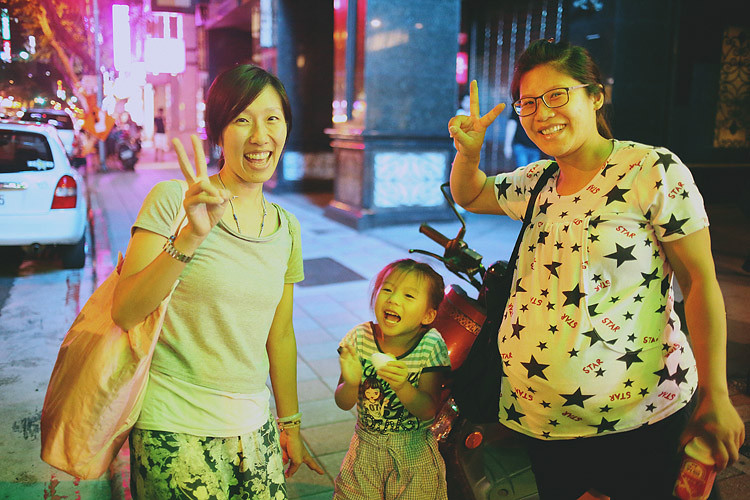 夜晚的醫院門口，孕婦與助產師比出手勢，姐姐站在兩人中間。