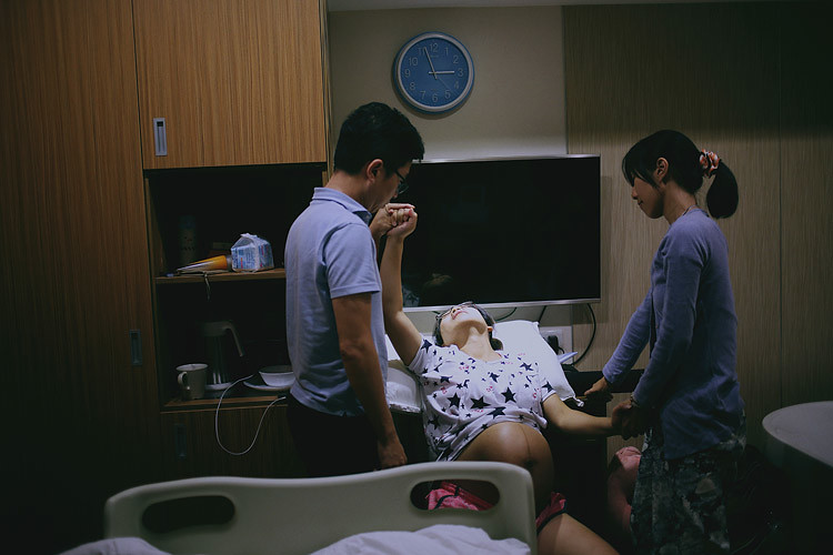 台北生產紀錄，孕婦冠鳯靠坐在待產床上，丈夫與助產師嘉黛分別握著她的手。